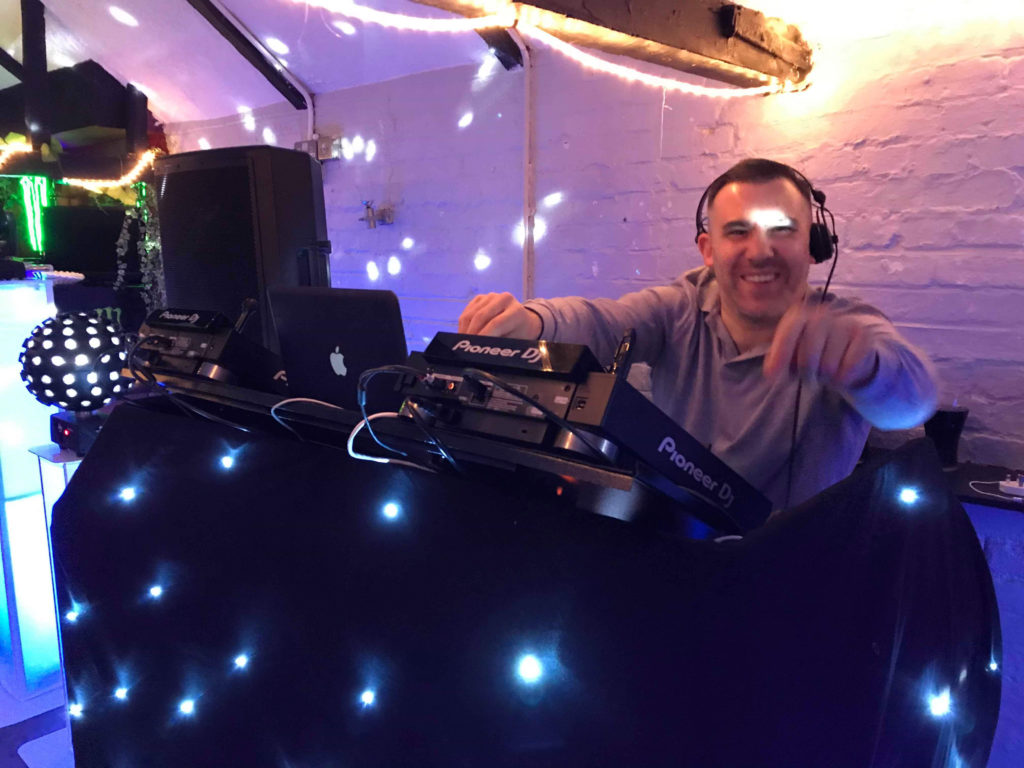 Maldon-based wedding DJ behind Mr Beats performing at the decks with professional DJ lighting