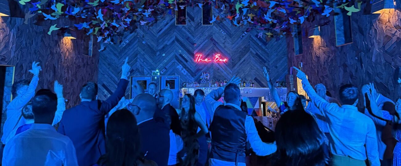 Wedding Dancefloor Celebration | Mr Beats Wedding guests dancing beneath blue lighting at a Mr Beats DJ celebration